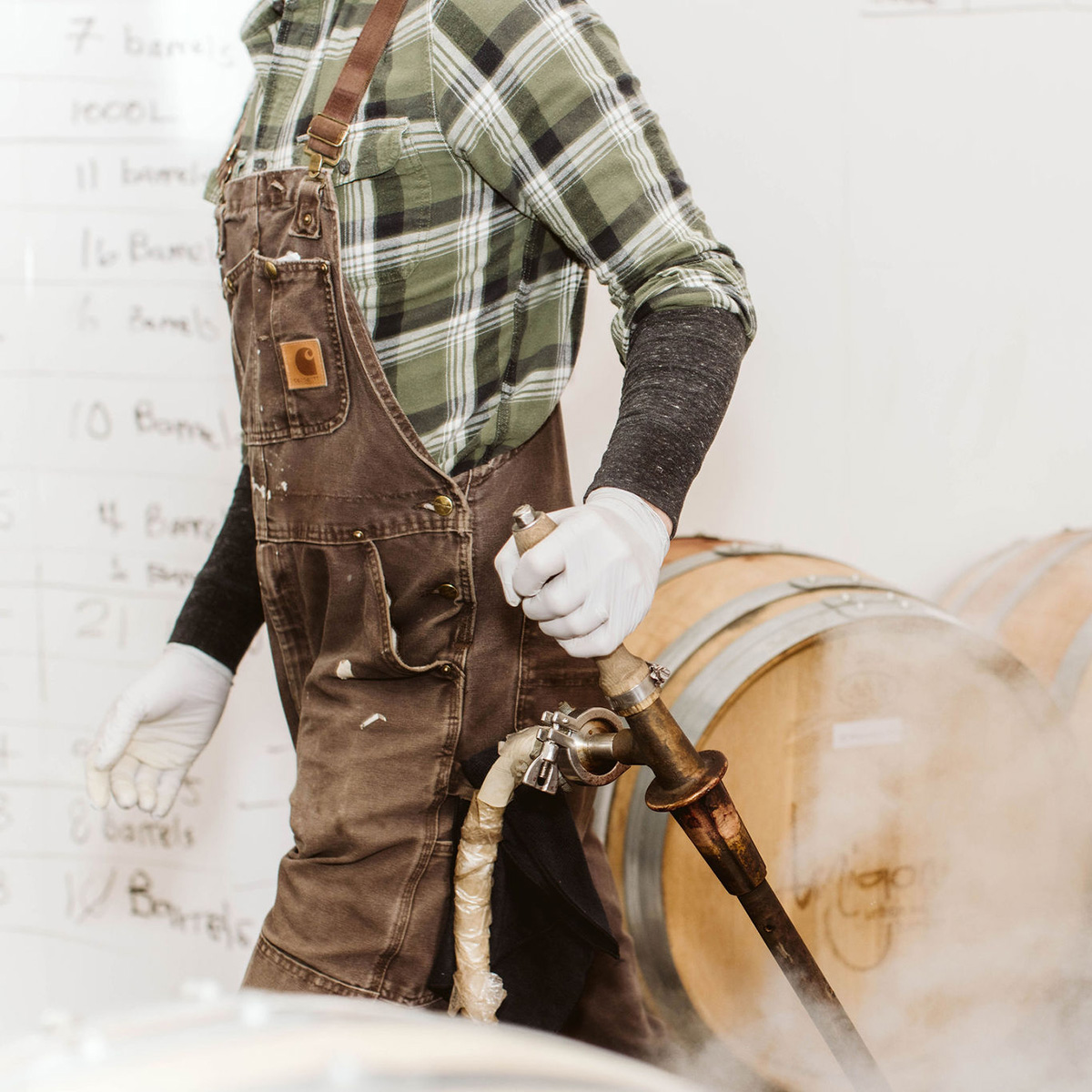 Man in plaid shirt and overalls working in the barrel factory of Amigoni Winery.