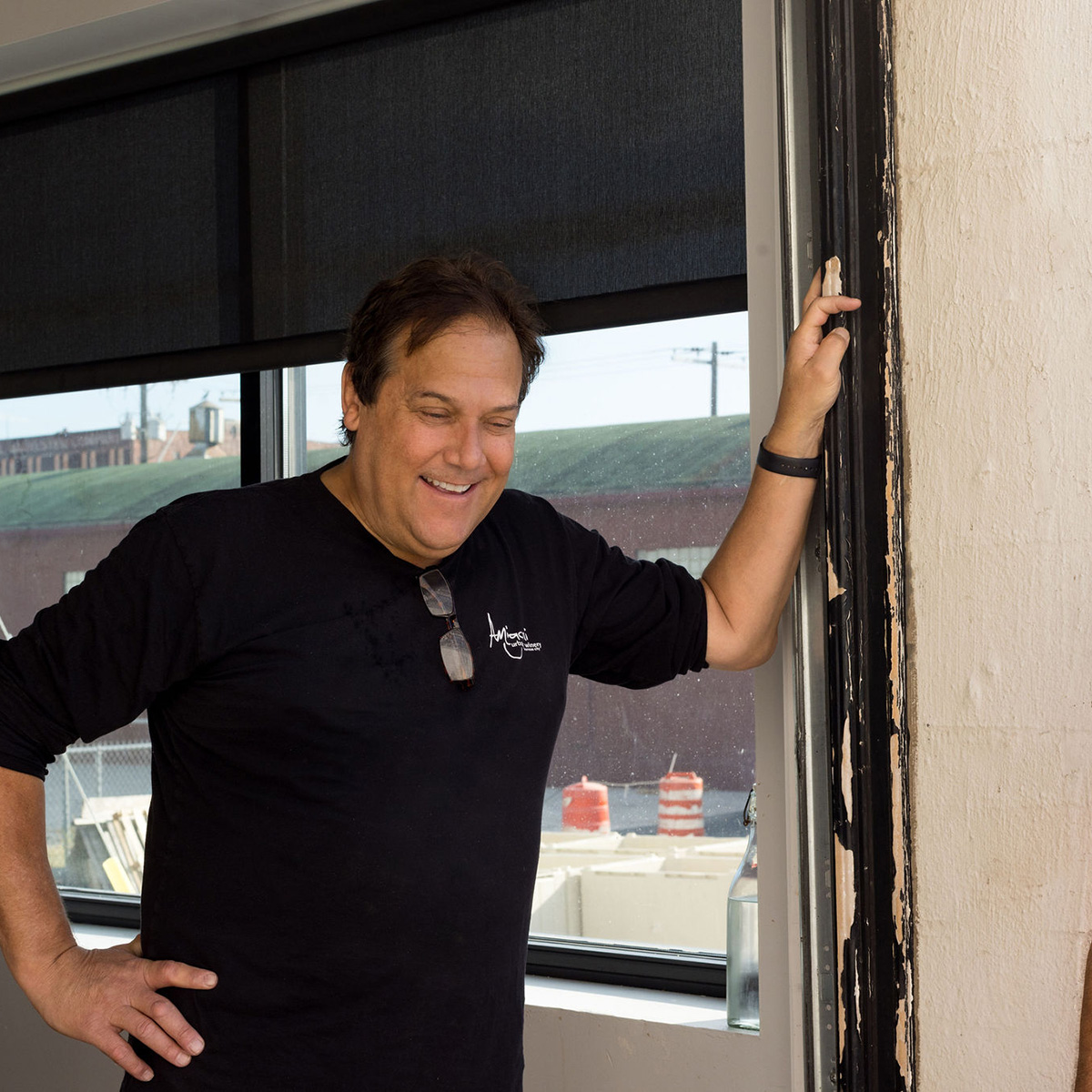 Owner Michael Amigoni propped up against a wall in the winery and smiling.